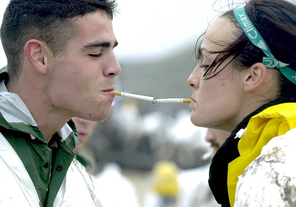 Una voluntaria ayuda a su compañero a encender un cigarrillo. <br><b>Efe</b>